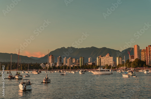 beach with people, modern buildings, mountains covered with trees and emerald sky of a sunset
