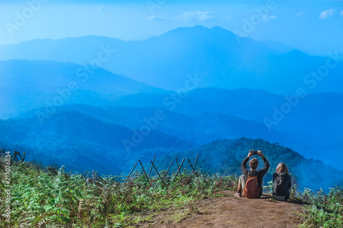 Couple Travelers Man and Woman with backpack sitting relaxed on mountain