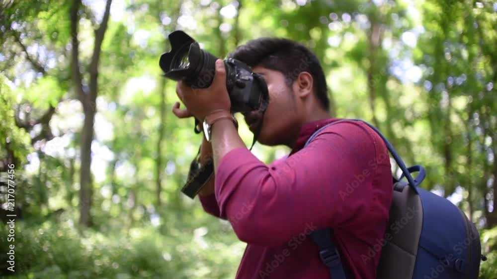 A photographer shooting photos of birds and trees in a forest with his DSLR camera in slow motion A photographer shooting photos of birds and trees in a forest with his DSLR camera in slow motion