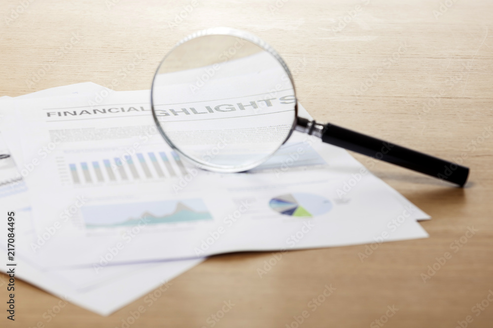 magnifier closeup with financial paper on the wood table. magnifier closeup with financial paper on the wood table.