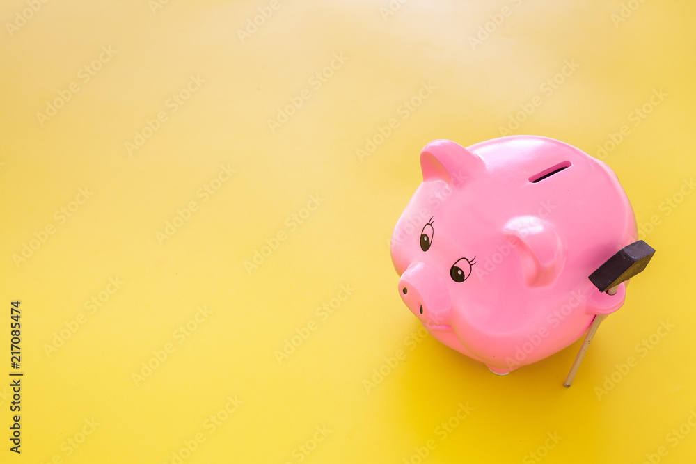 Piggy bank. Moneybox in shape of pig near hammer on yellow background copy space Piggy bank. Moneybox in shape of pig near hammer on yellow background copy space