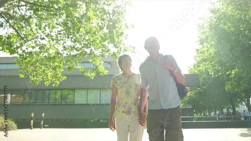 Slow motion steady cam view of an active senior caucasian tourist couple walking in london backlit by the sun themes of sightseeing active seniors direction on the move