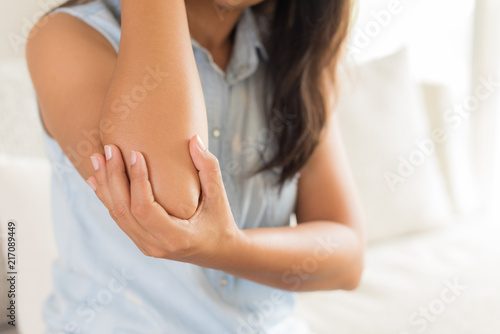 Close up woman having pain in injured elbow. Health care and arm pain concept.