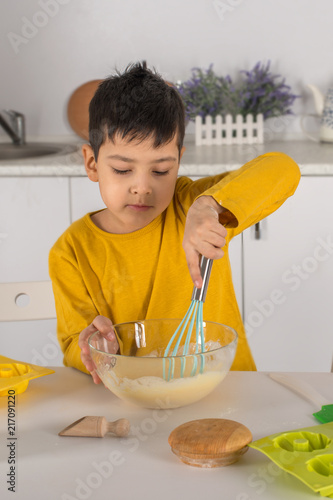 Tableau sur toile The little  boy  cooks cake in kitchen