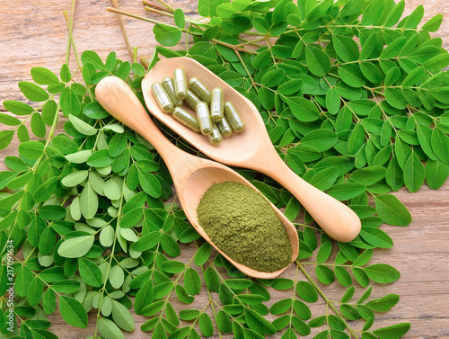 moringa leaf and powder capsule on wooden background photo