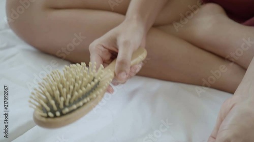 Woman hand pulling her hair fall from a comb wooden comb after hair combing.