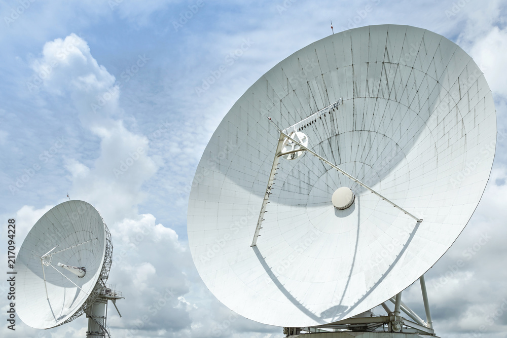 Fototapeta premium Big large white satellite dishes turn up skyward on blue sky in earth communication antenna system center station