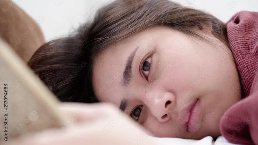 Attractive young asian woman using and looking at smart phone while lying on bed. Attractive young asian woman using and looking at smart phone while lying on bed.