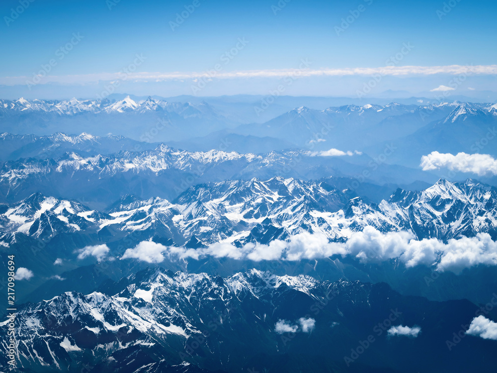 Fototapeta premium Aerial view from the airplane, clouds and snow over the mountains
