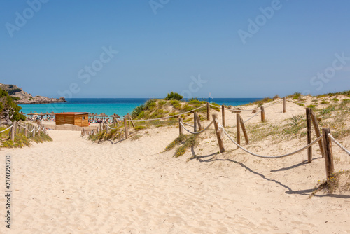 View of the Mediterranean Sea and sandy paths through the protected dunes to Cala Agulla beach on the Spanish holiday island of Mallorca