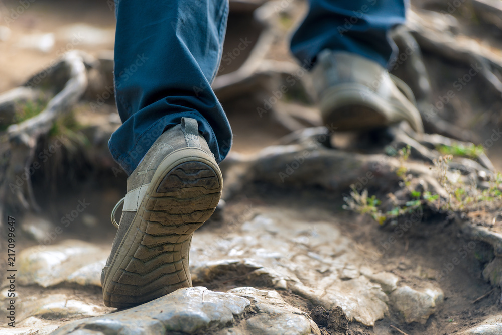 the tourist climbs up the mountain, his legs close-up on the stones the tourist climbs up the mountain, his legs close-up on the stones