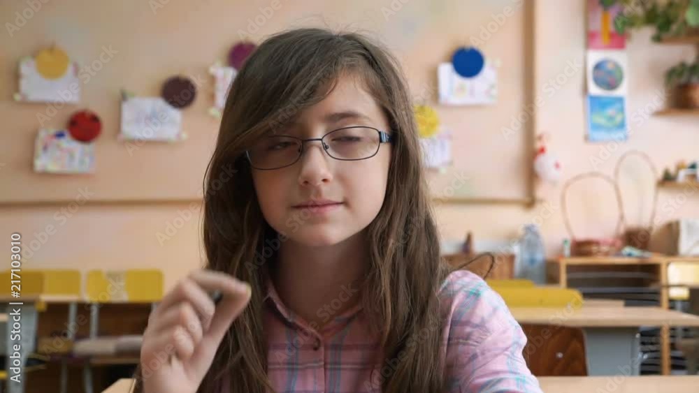 Teenage girl in glasses- high school student smiles to camera seated in classroom Teenage girl in glasses- high school student smiles to camera seated in classroom