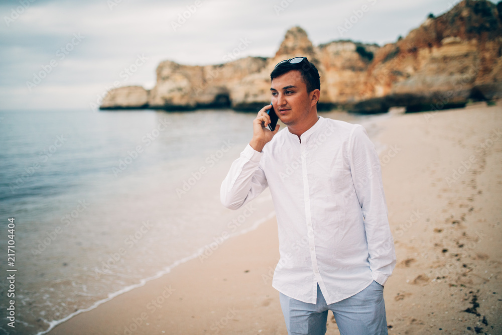 Young man is talk at his phone on beach in sunset Young man is talk at his phone on beach in sunset