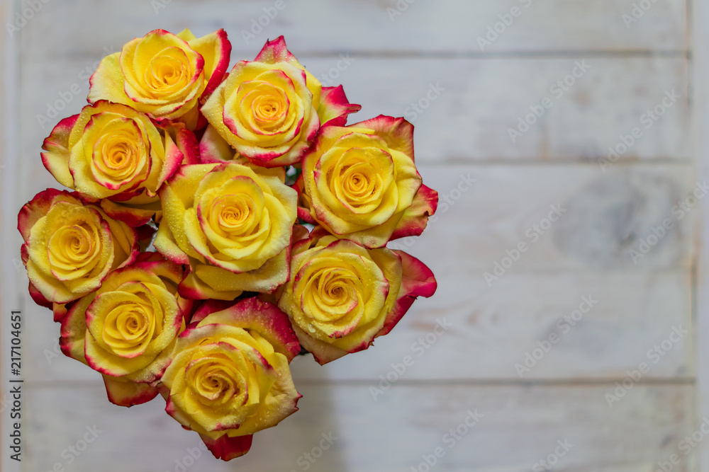 Naklejka premium top view of bunch of roses of yellow and red colors with water drops. greeting card concept with copy space