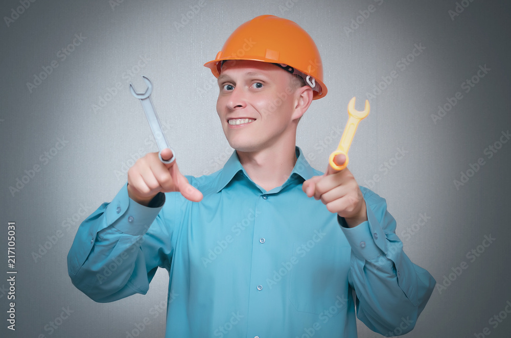 Happy builder worker with wrench tool in hands isolated on gray background. Happy builder worker with wrench tool in hands isolated on gray background.