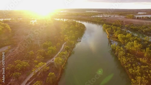 Slow aerial descend over Murray River at sunset with sun flare