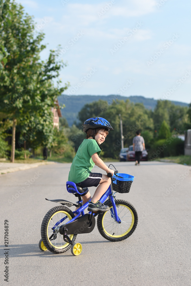 Five years old boy rides a bicycle in the city. Child riding bicycle outdoor on sunny day