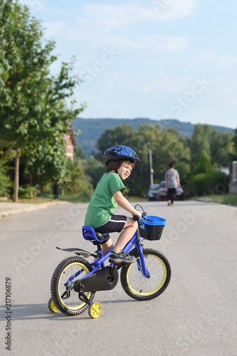 Five years old boy rides a bicycle in the city. Child riding bicycle outdoor on sunny day © Ivan