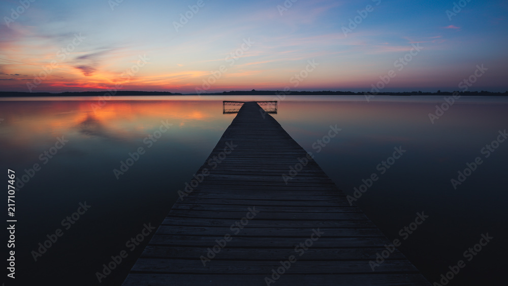 Obraz premium Old empty wooden jetty on lake, during sunrise.