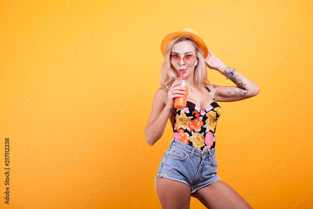 Attractive young woman drinking orange juice with sunglasses in studio Attractive young woman drinking orange juice with sunglasses in studio