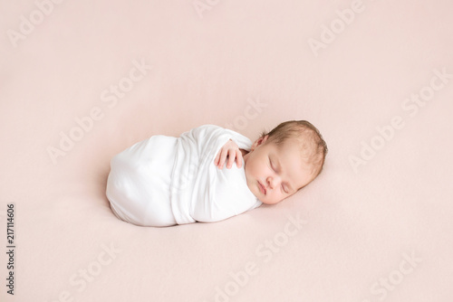 Newborn girl in white wrap on a pink background. Photoshoot for the newborn. 7 days from birth. A portrait of a beautiful, seven day old, newborn baby girl	