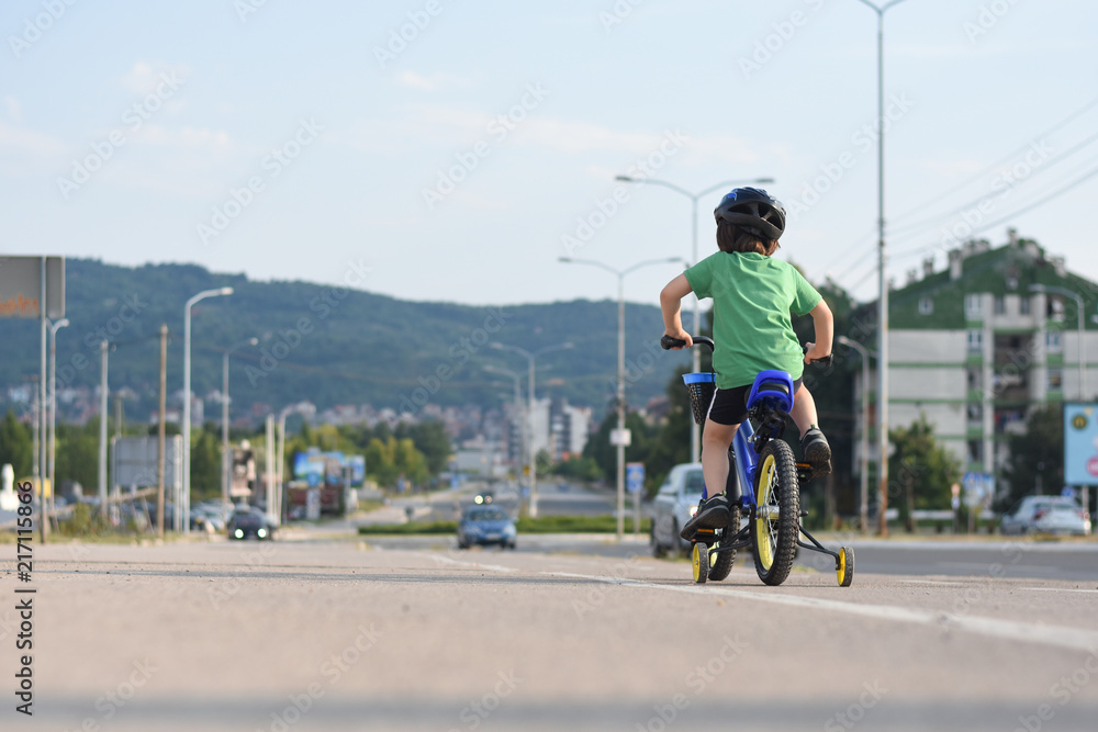 Obraz premium Five years old boy rides a bicycle in the city. Child riding bicycle outdoor on sunny day