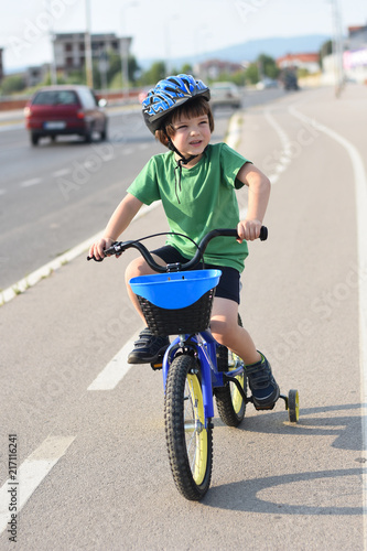 Fototapeta Naklejka Na Ścianę i Meble -  Five years old boy rides a bicycle in the city. Child riding bicycle outdoor on sunny day