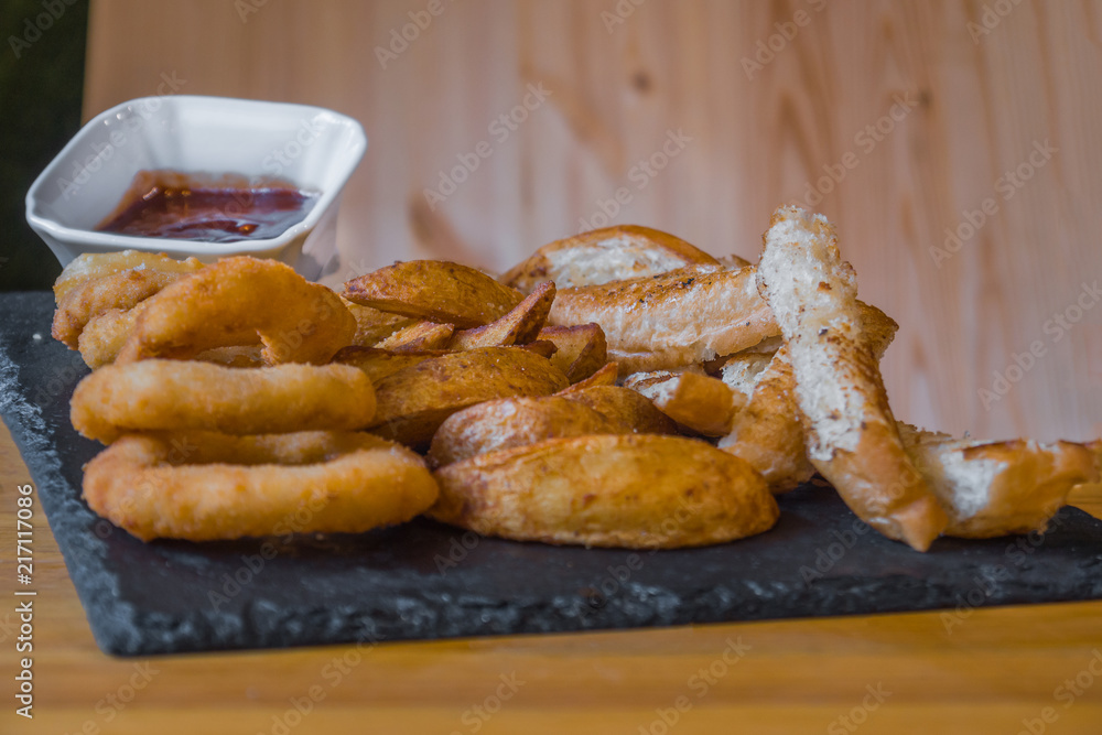 Assorted snacks for beer in the bar. Meat, cheese, onion rings on the grill and deep-fried