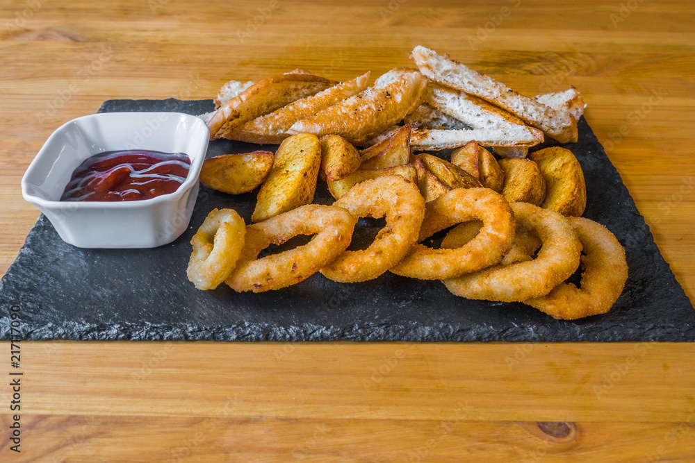 Assorted snacks for beer in the bar. Meat, cheese, onion rings on the grill and deep-fried
