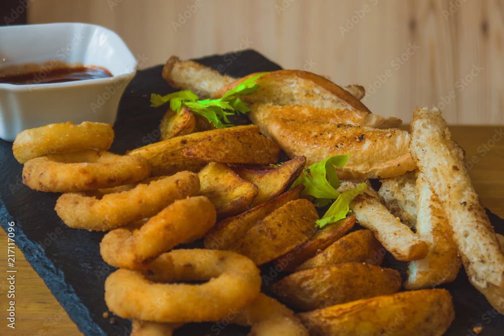 Assorted snacks for beer in the bar. Meat, cheese, onion rings on the grill and deep-fried