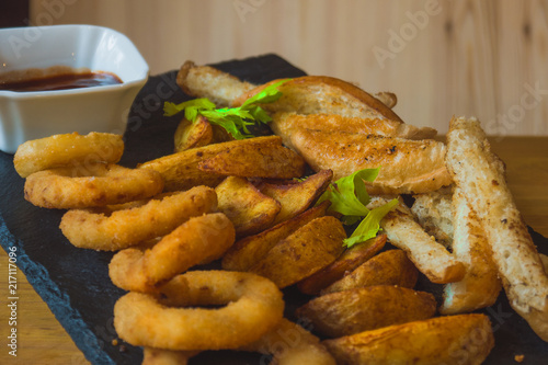 Obraz na płótnie Assorted snacks for beer in the bar. Meat, cheese, onion rings on the grill and deep-fried w salonie