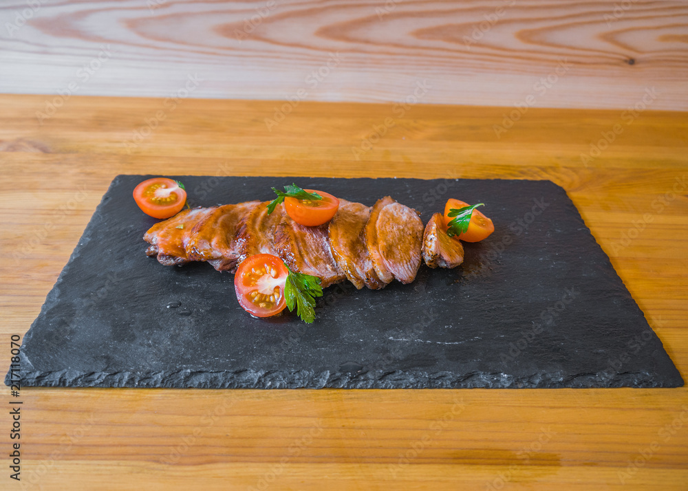 meat with vegetables on a stone board. tomatoes. and spices, a delicious dish