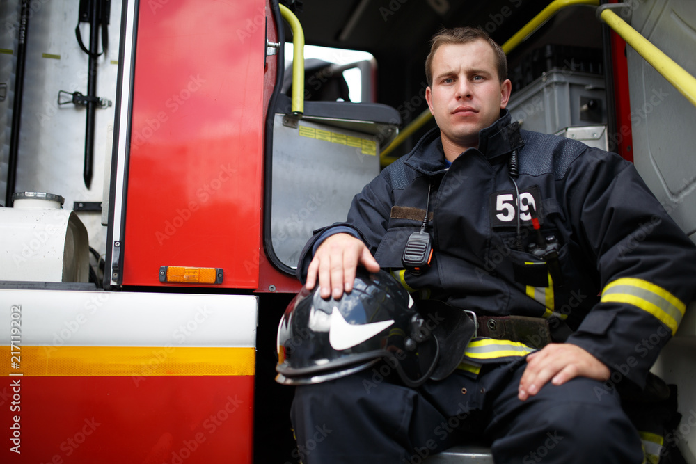 Photo of young fireman looking at camera in fire truck Photo of young fireman looking at camera in fire truck
