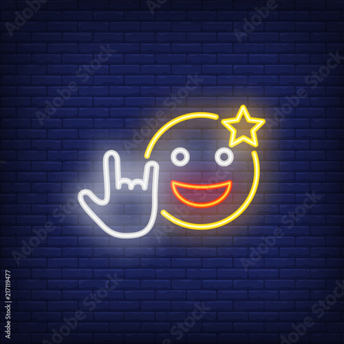 Excited emoticon with cool gesture neon sign. Star on smiley, showing rock symbol. Night bright advertisement. Vector illustration in neon style for rock concert and spectacular