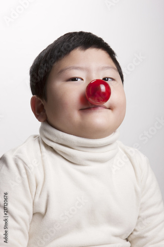 an asian little boy with red nose be happy on the white background.