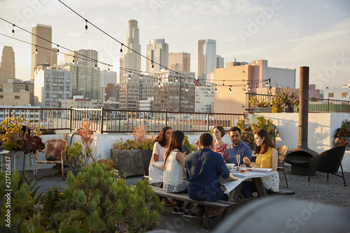 Friends Gathered On Rooftop Terrace For Meal With City Skyline In Background photo