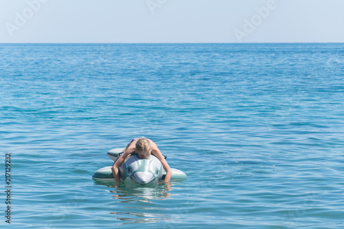 The girl is swimming on an inflatable toy-dolphin on the sea of the ocean. Rest on the water, vacation.