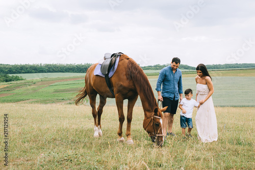 parents and son standing on green field with brown horse © LIGHTFIELD STUDIOS