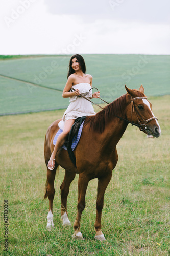 beautiful woman riding brown horse on field