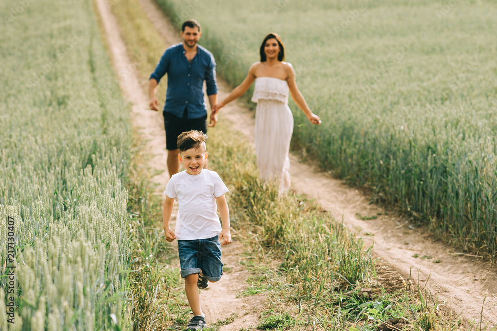 happy parents and son running on path in field happy parents and son running on path in field
