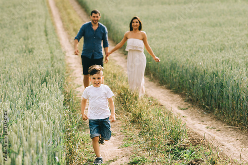 happy parents and son running on path in field