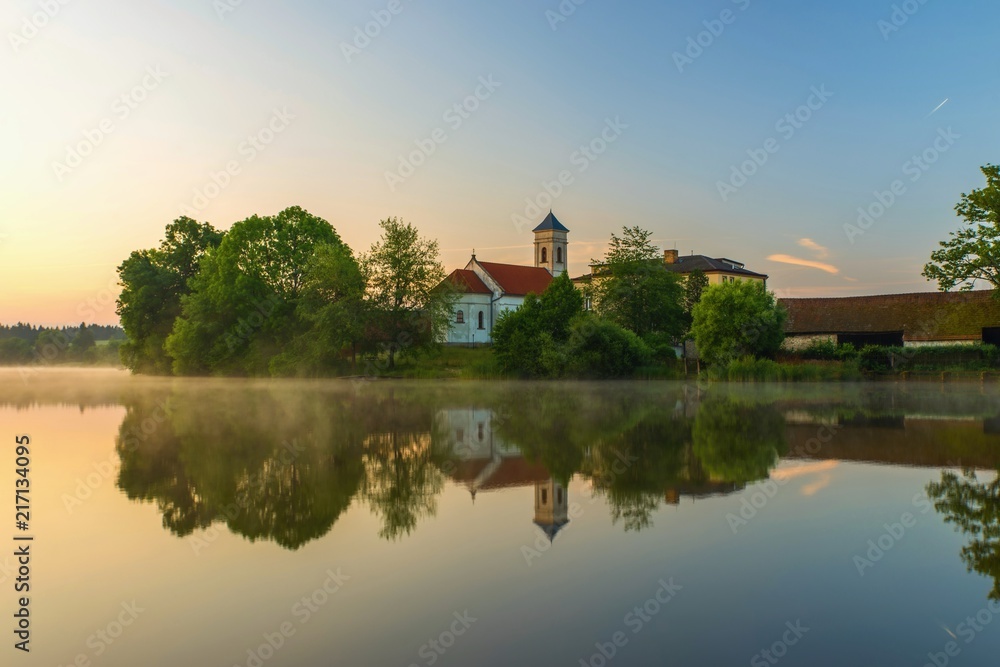 Fototapeta premium Church and tree on pond bank in sunrise, Blato.
