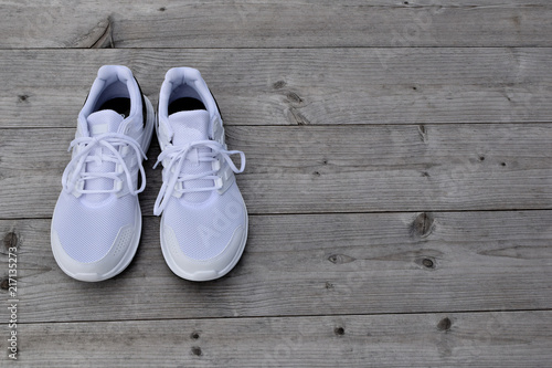 White new sneakers on grey weathered natural wood background with copy space for text.