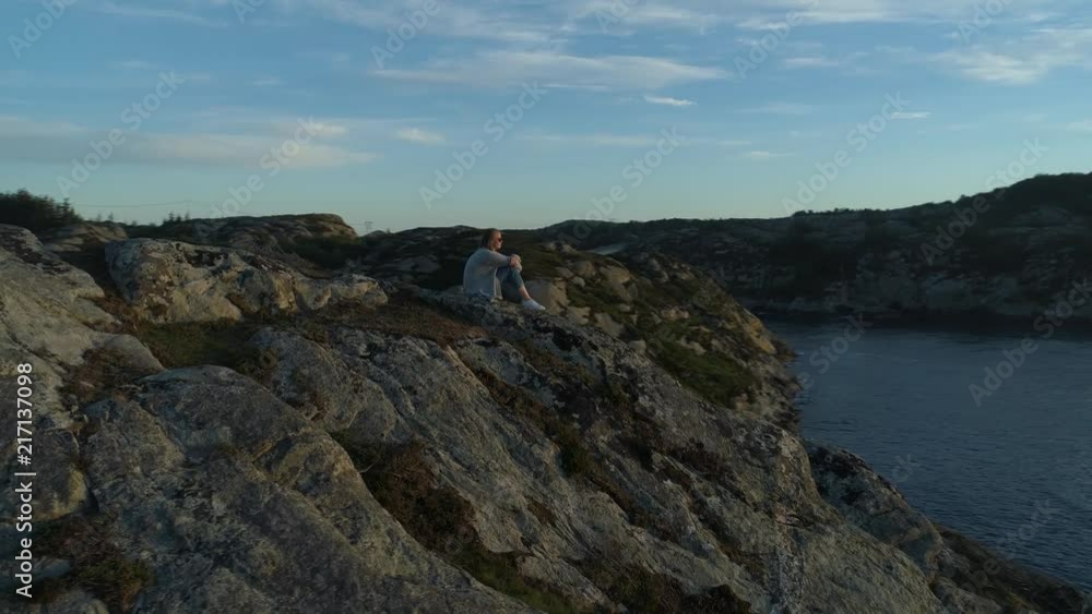 Panning drone shot of young girl on a mountain enjoying the sun setting in the horizon. Panning drone shot of young girl on a mountain enjoying the sun setting in the horizon.