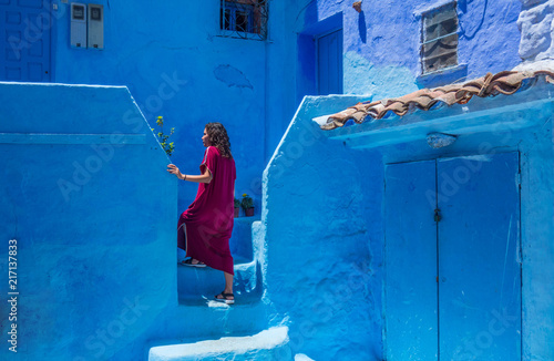 Woman with djellaba in  Chefchouen street, famous blue city. Traditional moroccan architectural details photo