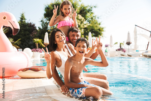 Happy young family having fun together at the swimming pool