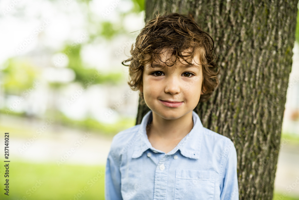 Cute Caucasian boy happily close to a tree Cute Caucasian boy happily close to a tree