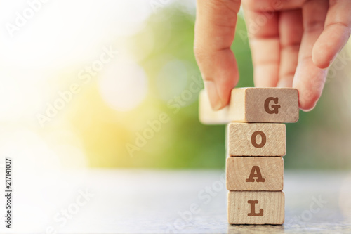 Hand putting the wooden toy with word GOAL for business plan concept