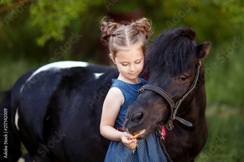 Cute little girl and pony in a beautiful park photo