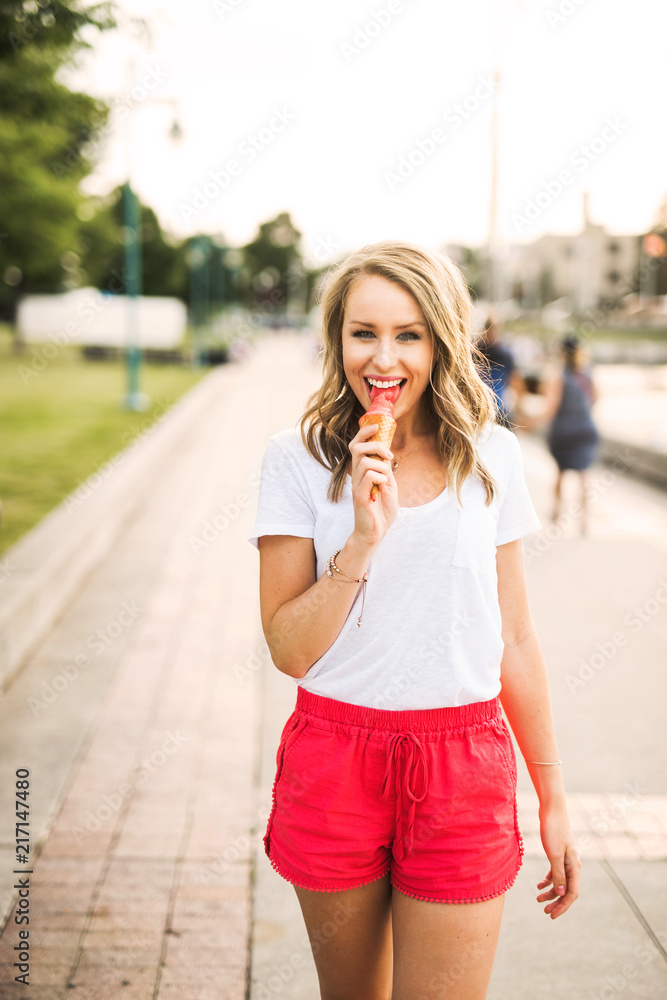 Fototapeta premium A beautiful, young woman enjoying ice cream by the marina